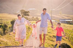 Family walking together through golden field during sunset photo session.