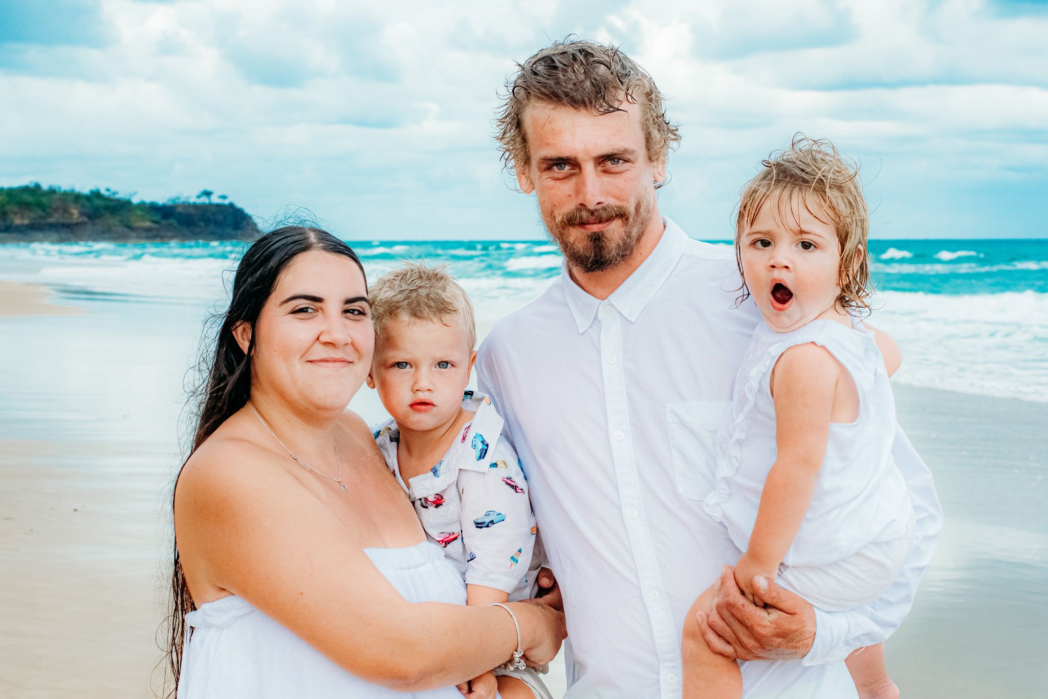 Family enjoying a sunny day at the beach with turquoise waters and white sand in the background.