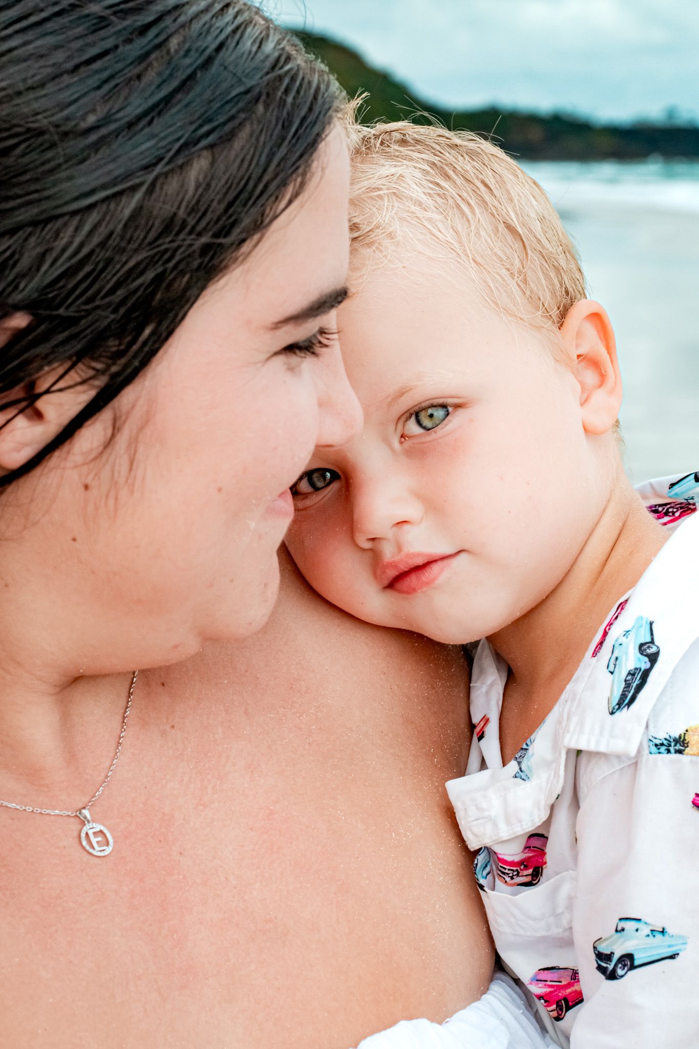 Tender moment captured in close-up against beach background.