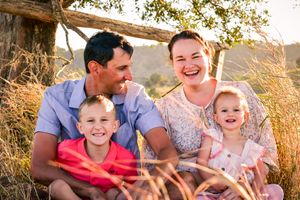 Family enjoying candid moments together outdoors in natural setting with golden light.