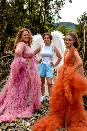 People wearing dramatic pink and orange tulle dresses posing by rocky landscape.