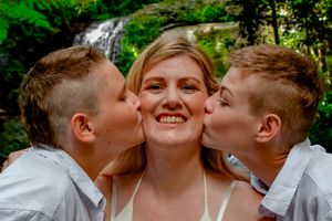Playful group photo showing affection and laughter in a natural outdoor setting.