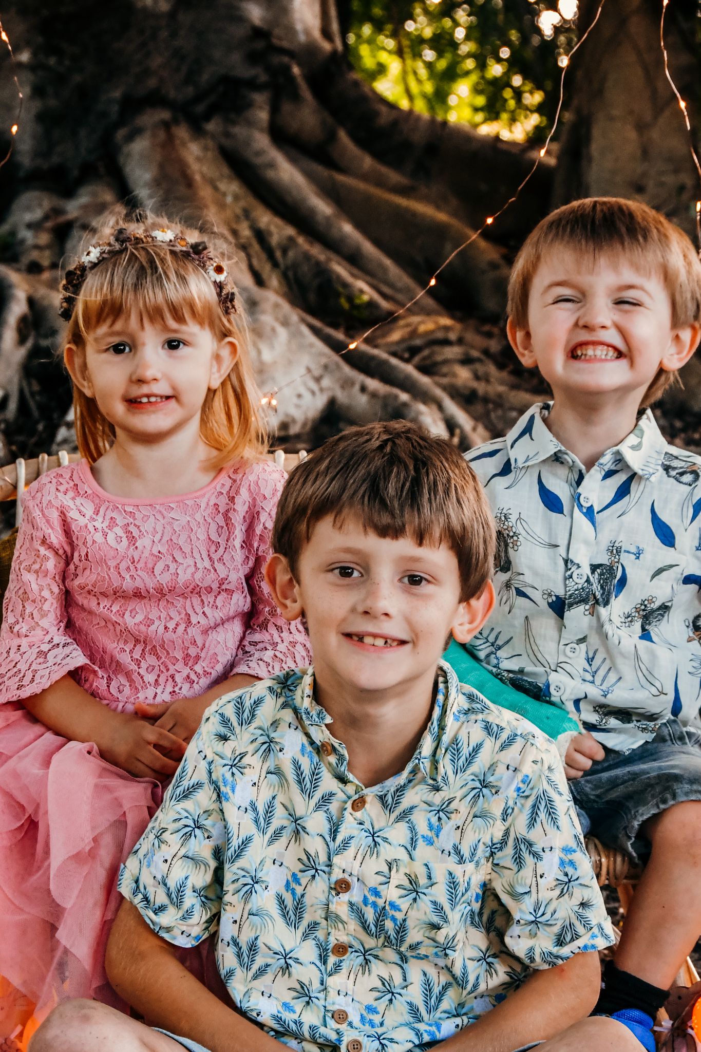Children in coordinated pink and blue floral outfits smiling outdoors.