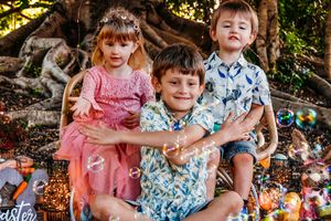 Candid outdoor family photo with children in matching tropical print shirts.