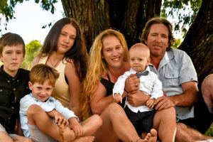 Family gathered together under a large tree for a casual outdoor portrait.
