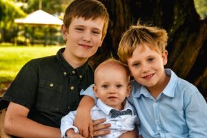 Outdoor family photo under golden sunlight with coordinated casual outfits.