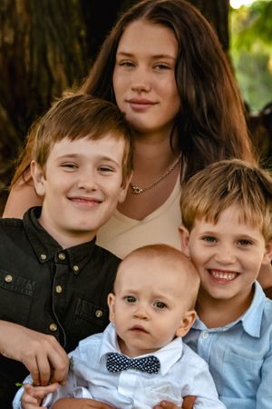 Close-up portrait of family members with genuine smiles and a baby wearing a bow tie.