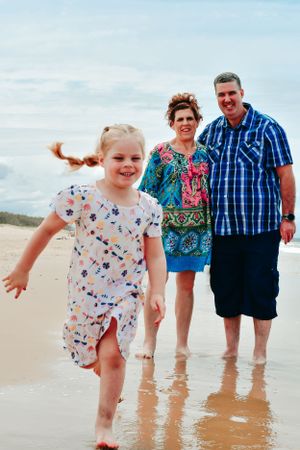 Family members playing and splashing in shallow beach water on a sunny day.