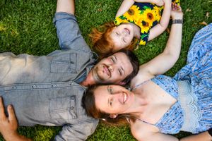 Couple lying on grass with sunflowers enjoying a summer day.
