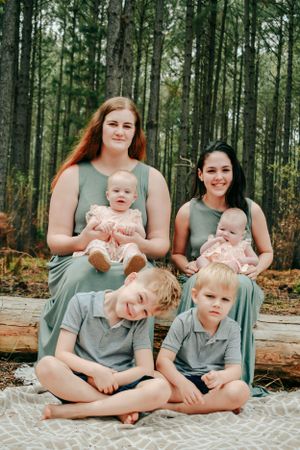 Casual family portrait session in a wooded setting with everyone wearing matching gray attire.