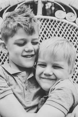 Black and white close-up portrait of two young siblings sharing an affectionate moment.