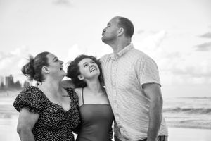 Black and white beach portraits capturing intimate family moments at sunset.