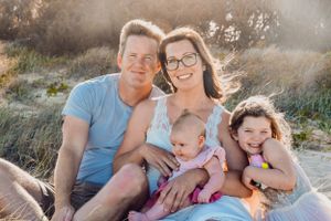 Candid family portrait session in warm sunset light among coastal grass.
