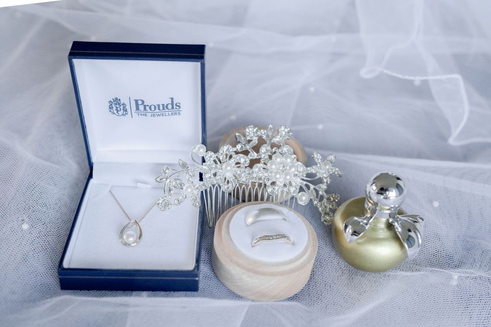 silver crystal and pearl hair comb sitting with white gold wedding rings, silver and pearl necklace and gold and silver