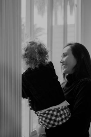 Black and white silhouette of parent and child by window sharing a loving moment.