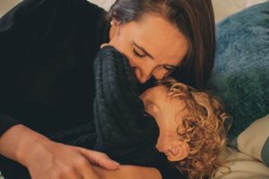 Intimate close-up of parent and child sharing an affectionate moment on a teal couch.