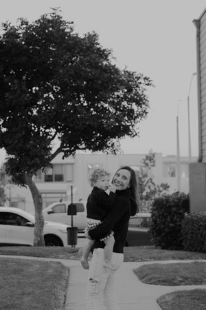 Black and white outdoor portrait capturing playful movement under a large tree.