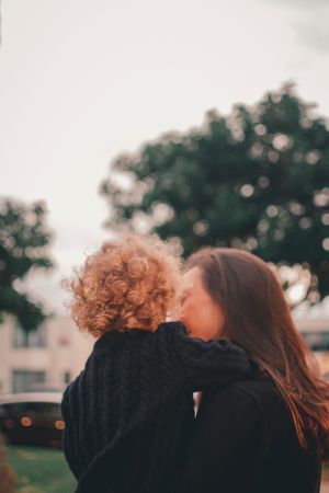 A tender moment outdoors at sunset as one shares a loving connection with another against a backdrop of trees.