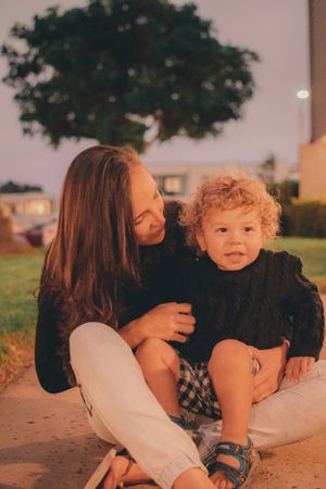 A warm sunset photo showing an affectionate moment shared outdoors beneath a large tree.