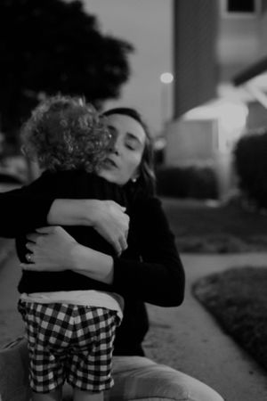 An intimate black and white photograph capturing an emotional embrace on a pathway at dusk.