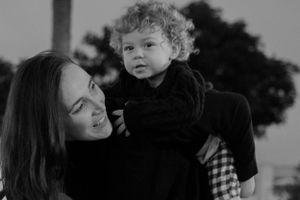 Black and white photo of a parent and toddler sharing a joyful outdoor moment together.