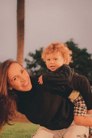 Parent and child with curly hair sharing a candid bonding moment outdoors.