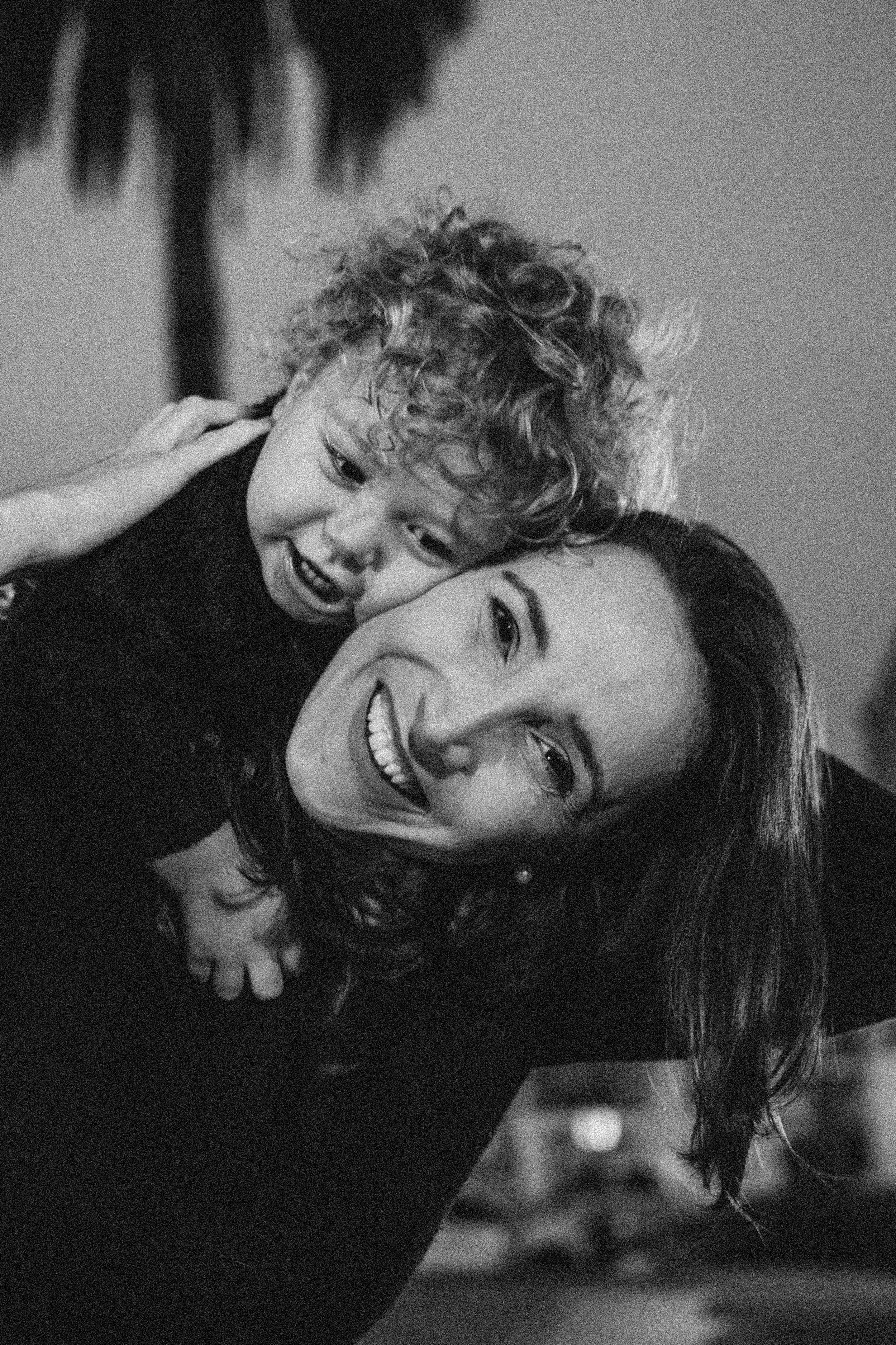 Black and white photo capturing playful interaction between parent and child.
