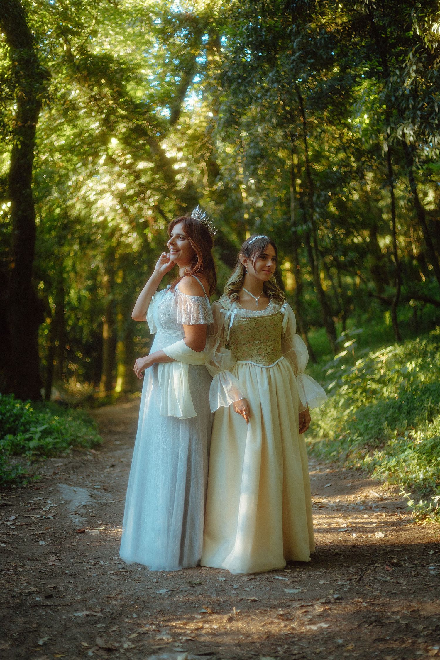 mãe rainha humana e filha princesa elfo de vestido e coroas no meio de caminho na floresta etéreo fantasia princesscore