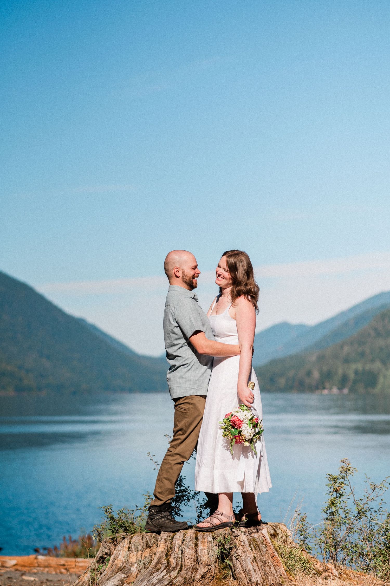 couple laughing while on stump with Lake Crescent in background. Photo by Tori Shults