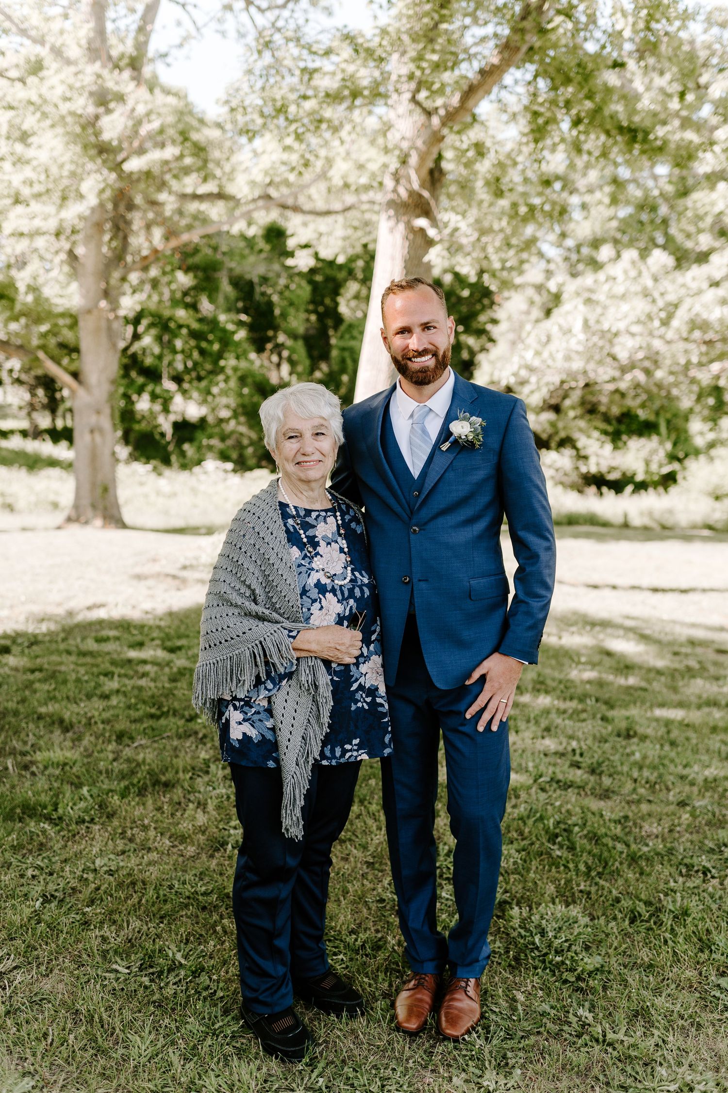 Family members pose together on grassy lawn for formal wedding portraits.