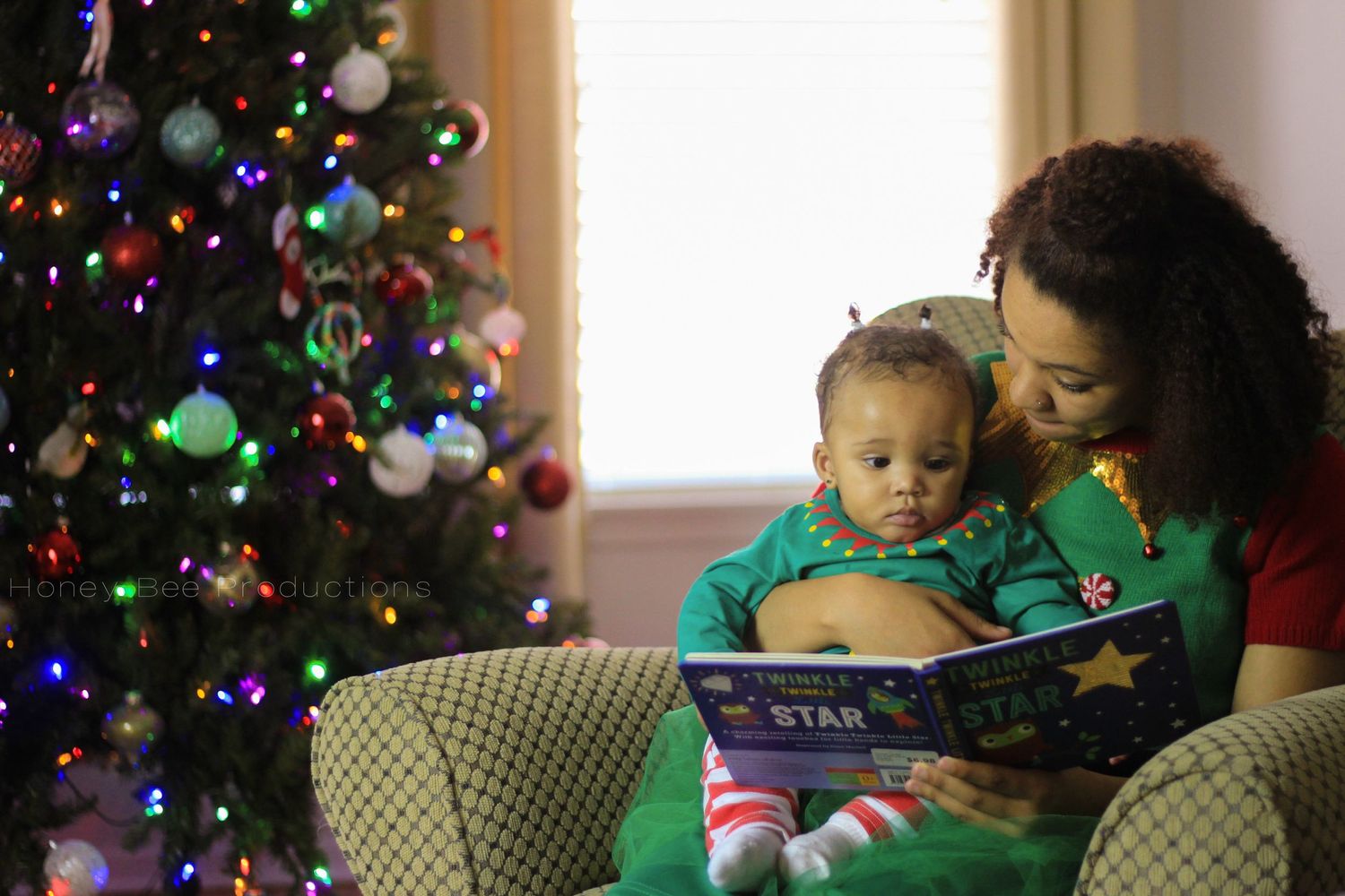 Christmas photo of a woman holding a baby and reading a book.