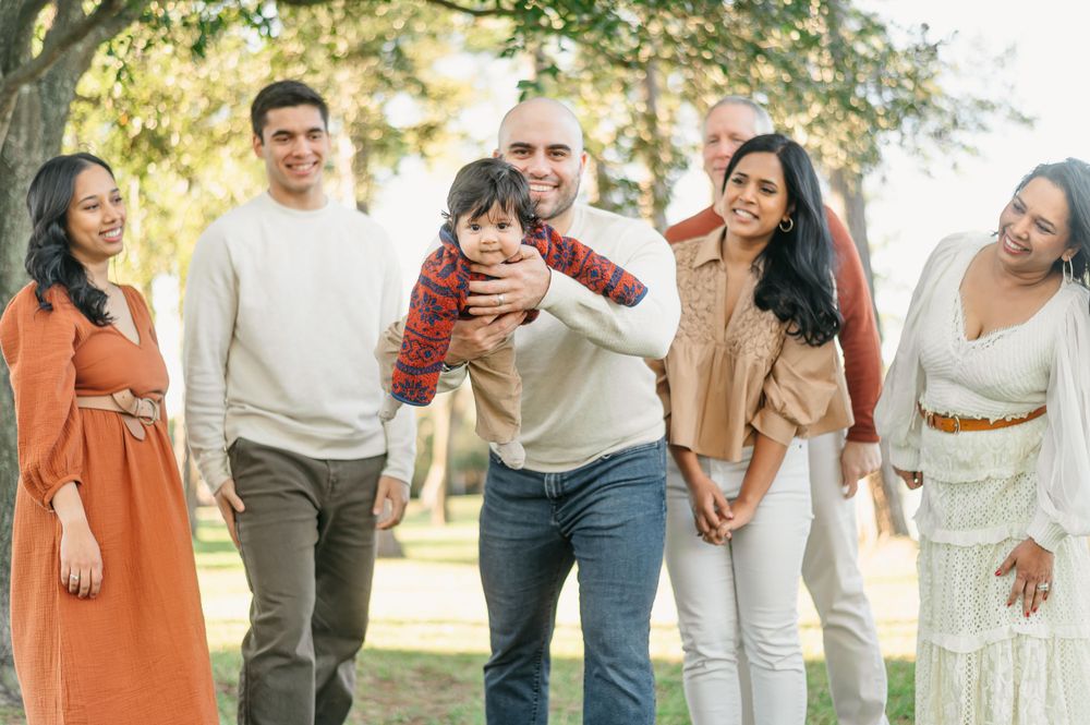 Multi-generational family enjoying a playful moment together in a sunny park.