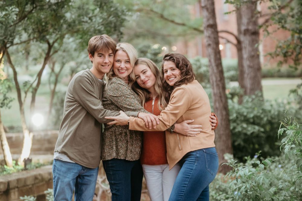 Group hugging and laughing together during outdoor family photo session.