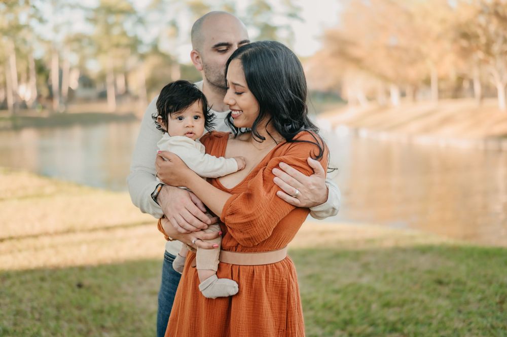Tender family moment captured by a lake with warm autumn colors.