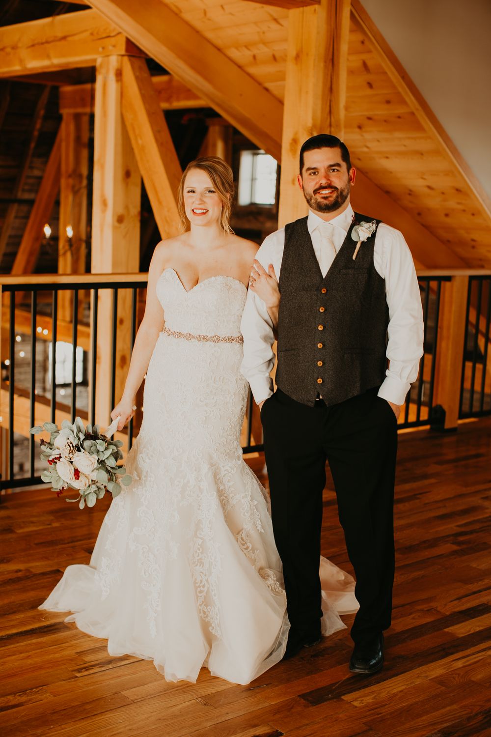 Bride and groom walking together on hardwood floors of elegant rustic timber barn wedding venue.