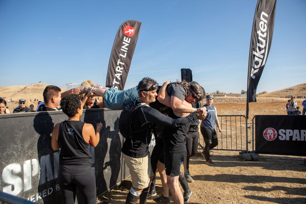 A group huddles together at an outdoor sporting event with promotional banners visible.
