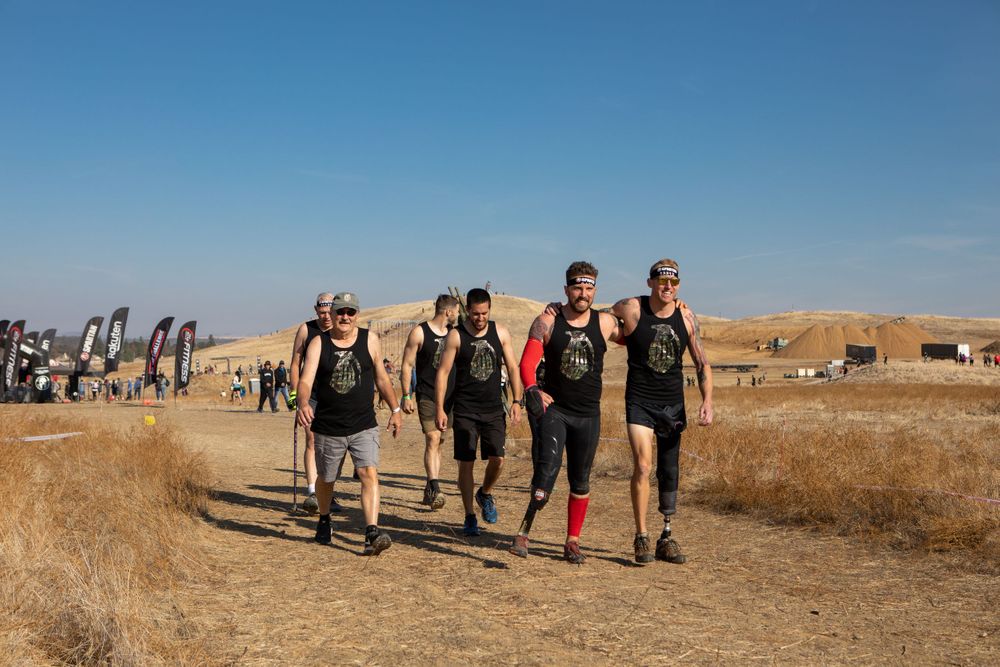 Athletes walk through a desert landscape during an outdoor competition event.