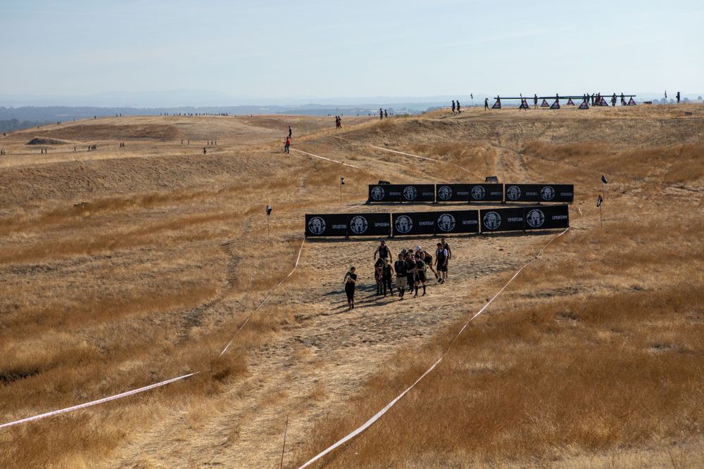 Aerial view of obstacle course setup with black barriers on dusty terrain.