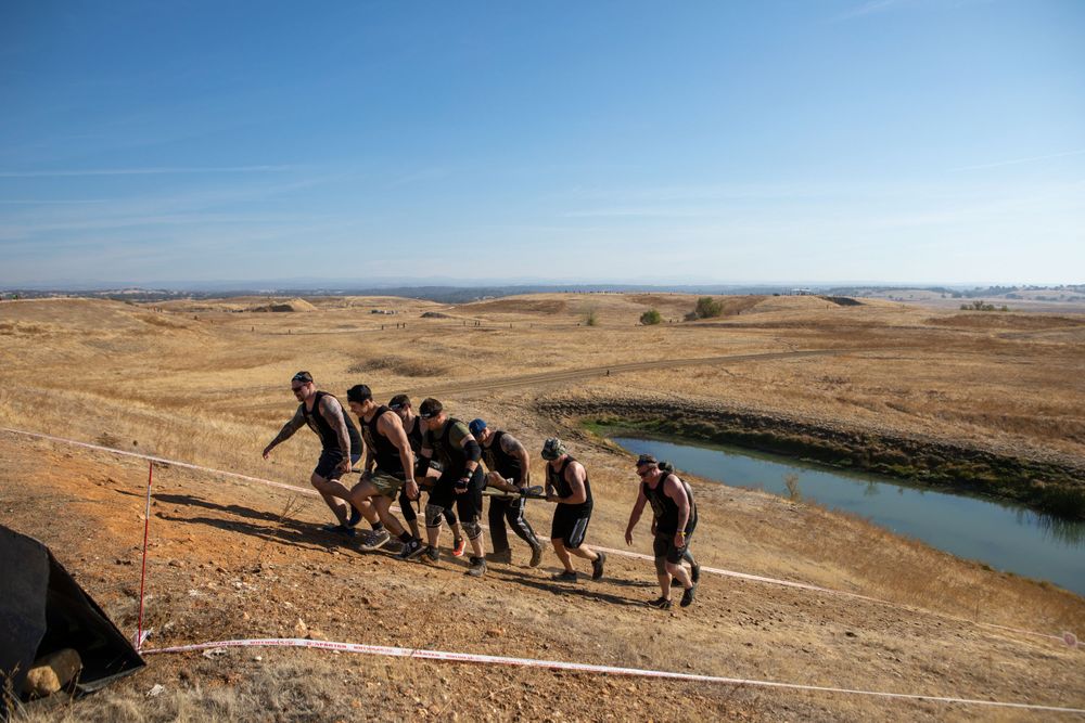 Line of participants hiking along ridge trail with river view in background.