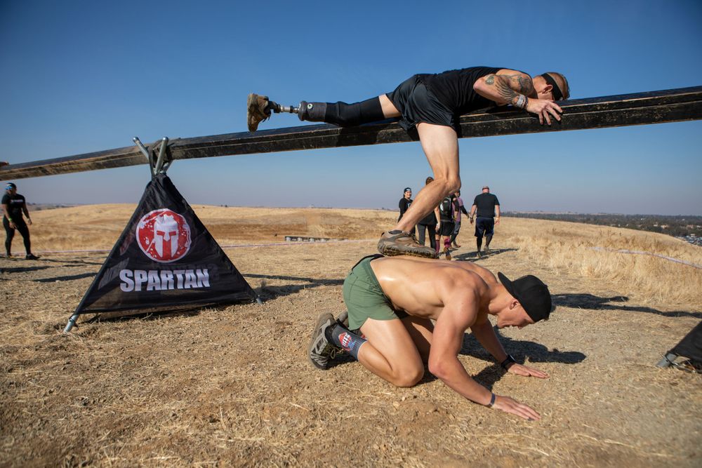 Athletes tackle challenging obstacles during a Spartan Race event in a desert landscape.