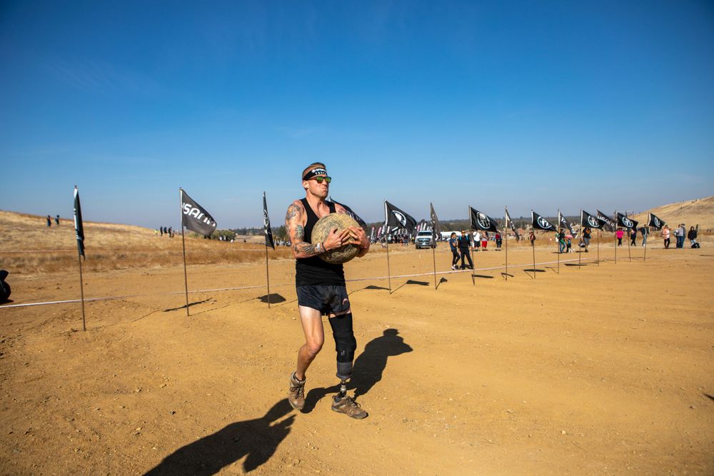Runner navigates through flag-lined course during desert obstacle race competition.