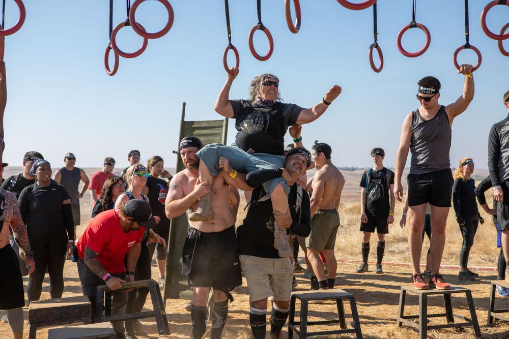 Athletes cheer and celebrate during obstacle course race completion.