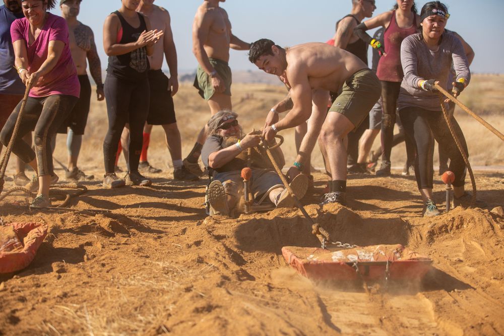 Competitors tackle muddy obstacles during intense outdoor race event.