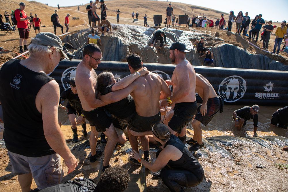 Competitors work together to overcome a challenging obstacle during an outdoor race event.
