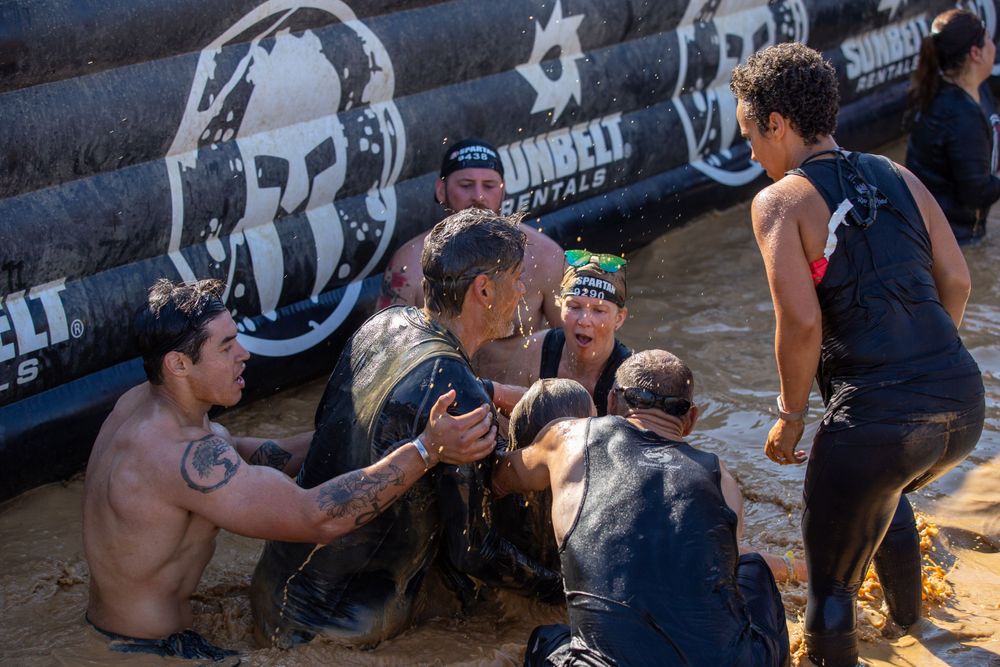 Athletes rest and hydrate during an outdoor obstacle course competition in a desert environment.