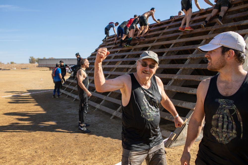 Participants navigate wooden obstacles during an outdoor endurance event in a desert setting.