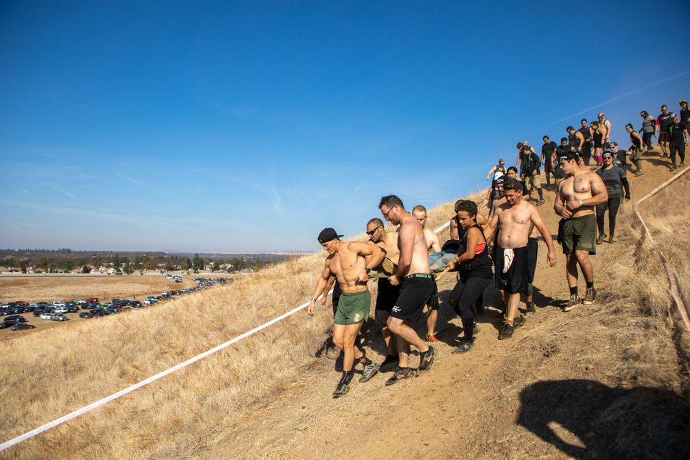 Competitors descending a steep hill during a desert obstacle course race.