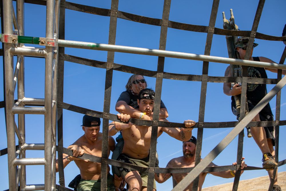Competitors climbing through a wooden frame structure during an obstacle course race.