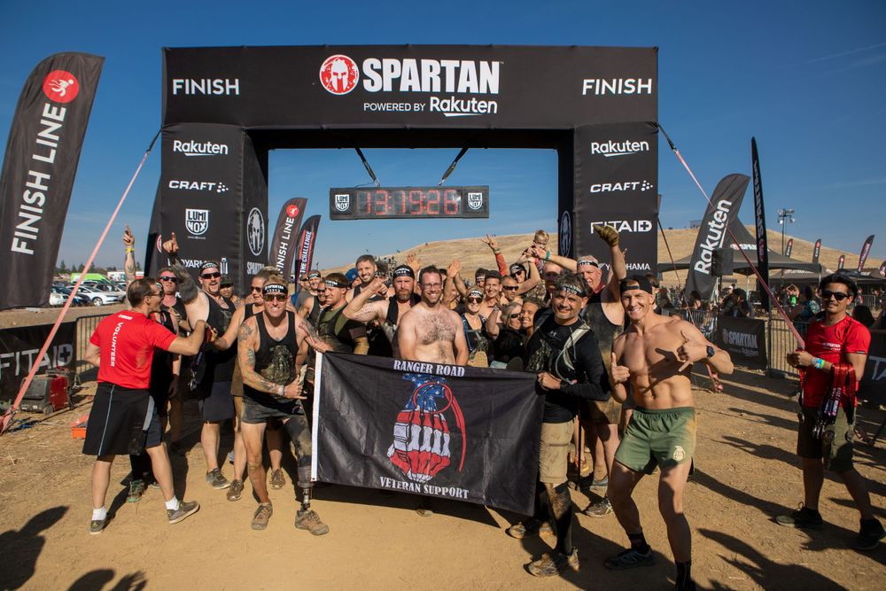 Enthusiastic participants celebrate at the Spartan Race finish line under a branded arch.
