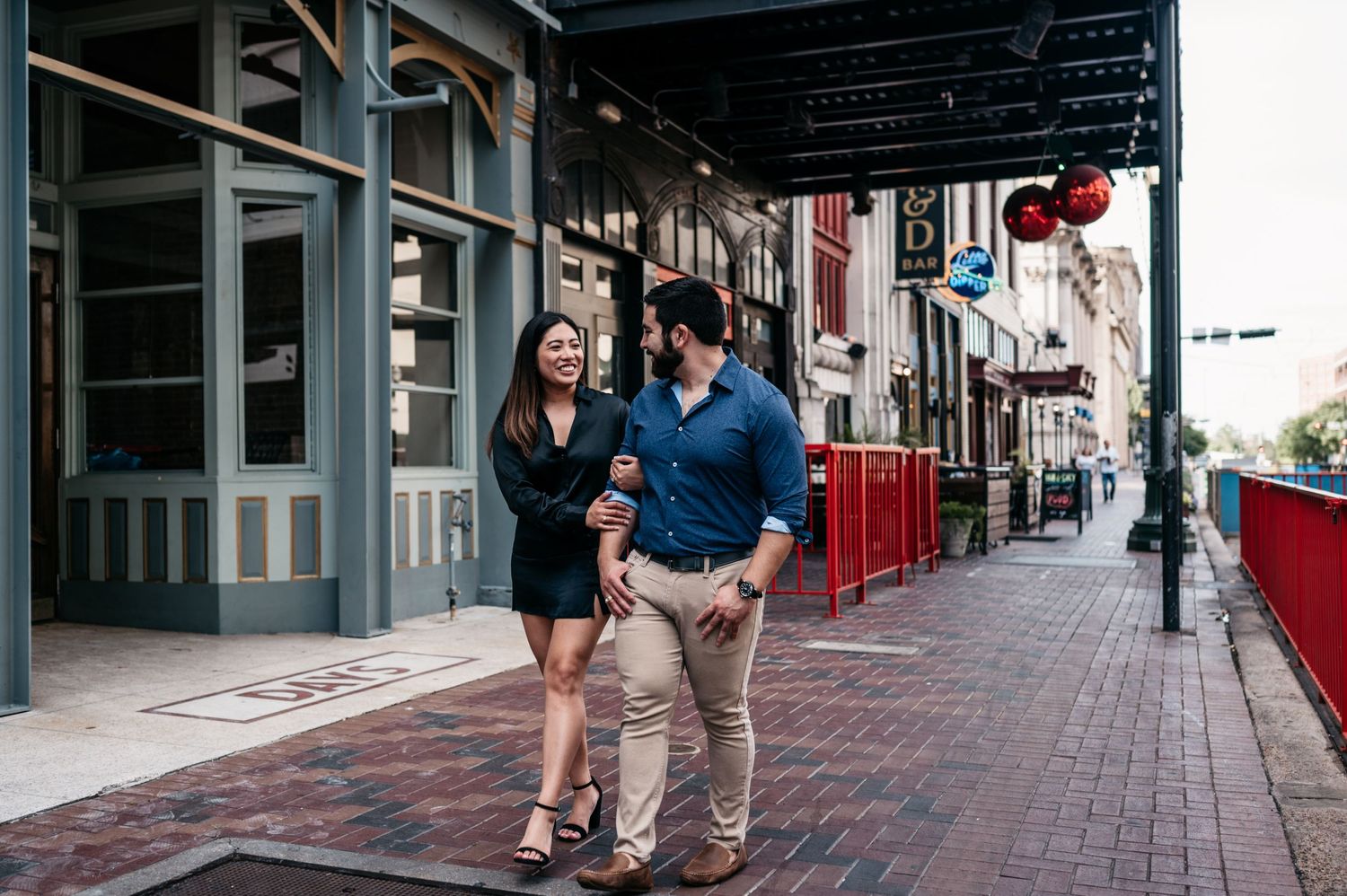 A couple walks together along a historic storefront with red awnings.
